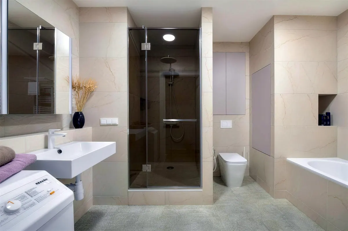 Beige bathroom with a glass shower, wall-hung toilet and tub