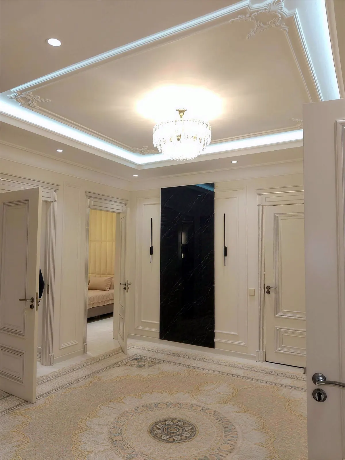 Entry hall with paneled walls, a lit tray ceiling and crystal light