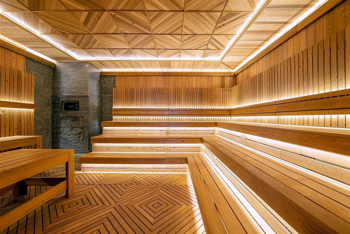 Sauna with tiered cedar benches and a stone heater wall