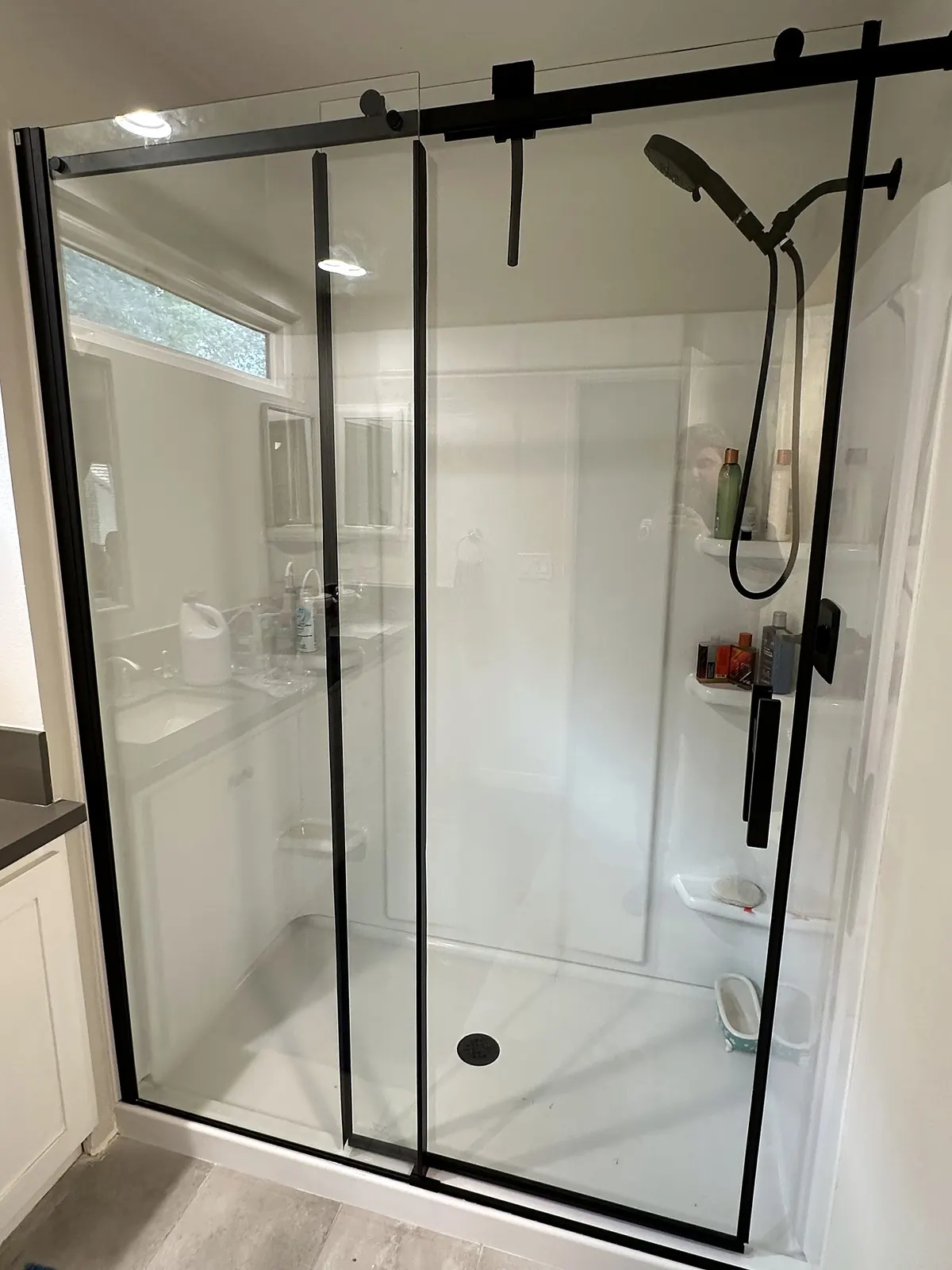 Walk-in shower with a clear glass sliding door and matte black hardware