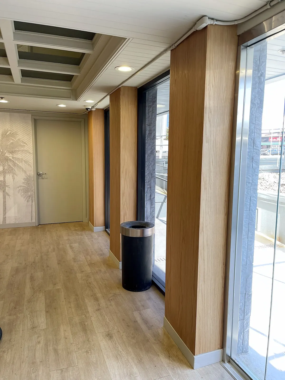 Office building hallway with wood-clad columns and vinyl plank floors