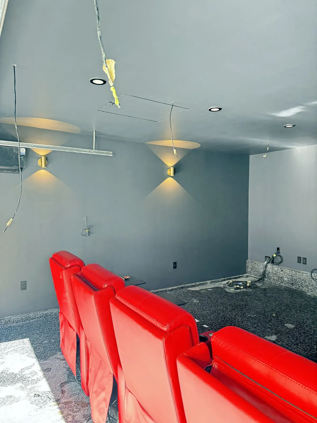 Finished home theater in a converted garage with red recliners and brass wall sconces