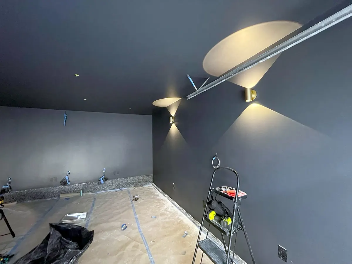 Dark home theater walls lit by brass sconces before the seating went in