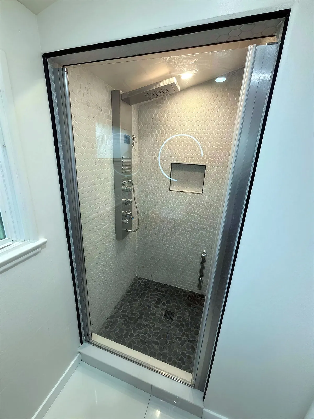 Walk-in shower with white hexagon marble mosaic and a glass door in a Van Nuys bathroom